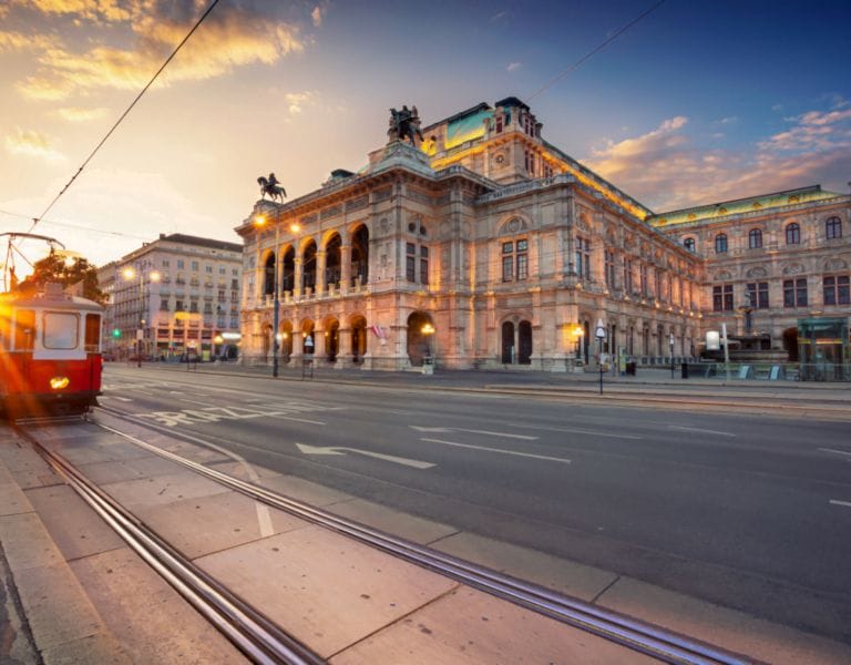 Historic building in Vienna with a traditional red tram passing by
