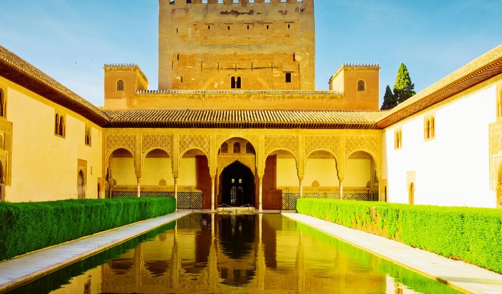 Courtyard of Alhambra Granada featuring intricate Moorish architecture with arches and a central fountain.