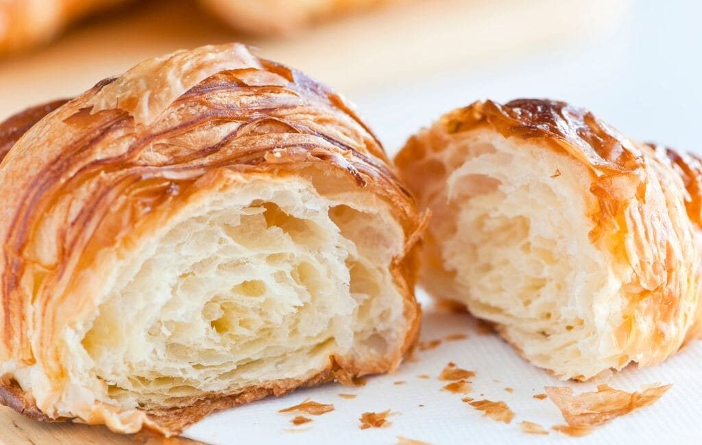 Freshly baked croissants on a baking tray.
