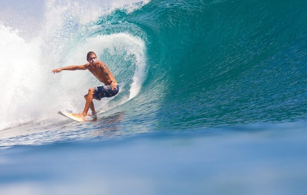 Surfer riding a wave at Croyde Beach against the backdrop of Croyde Bay's scenic coastline