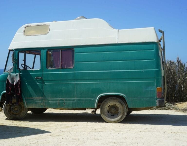 Vintage surfcamper parked on a tranquil beach at dawn in Ericeira, Portugal