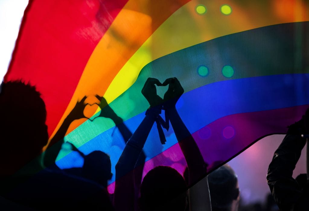 Dancing people with an LGBTQ flag, celebrating diversity and community.