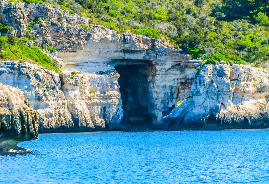 Cave on Menorca viewed from the water with cliffs and blue sea