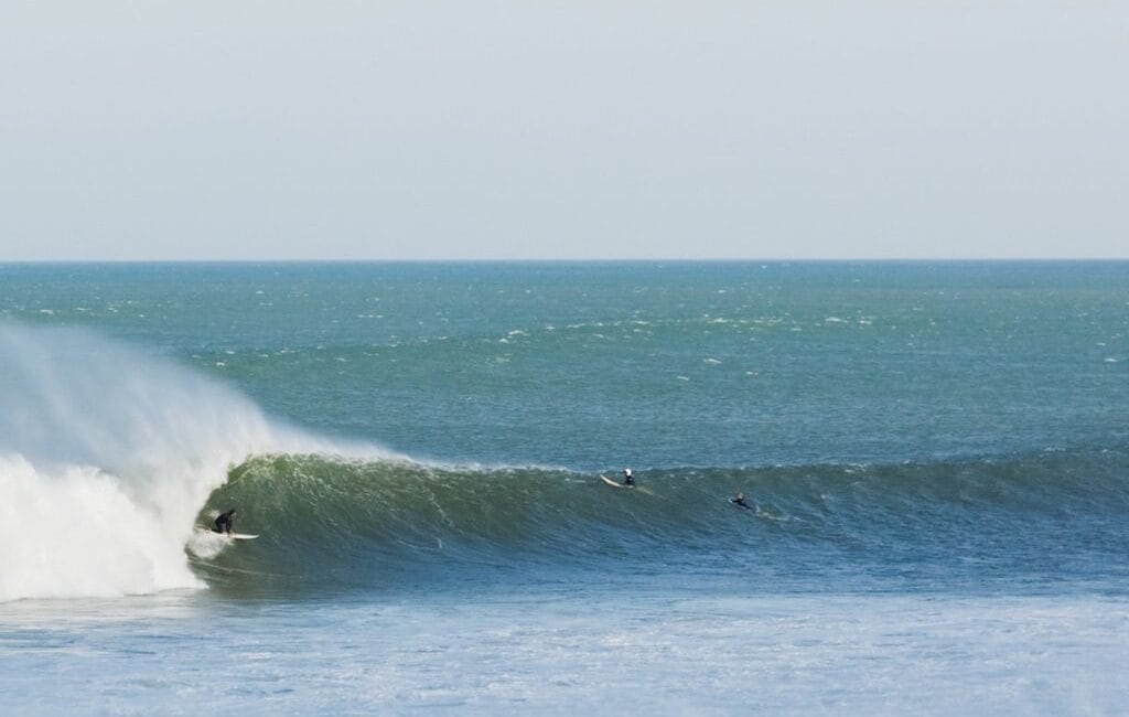 Surfer riding the famous left-hand wave in Mundaka, with the Basque Country's stunning scenery in the background.