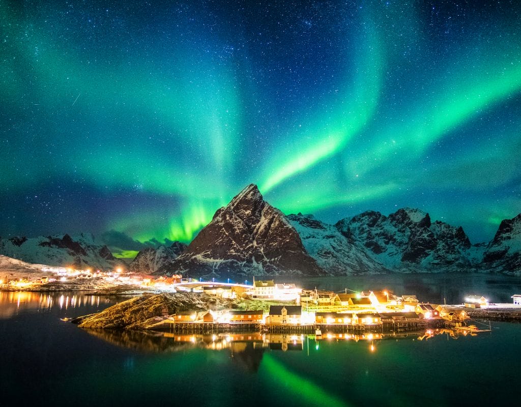 Famous Northern Lights illuminating the Norwegian fjords, casting a magical glow over the dramatic landscapes
