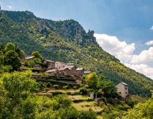 Old village on a hillside with mountains and green meadows in Parc National des Cévennes