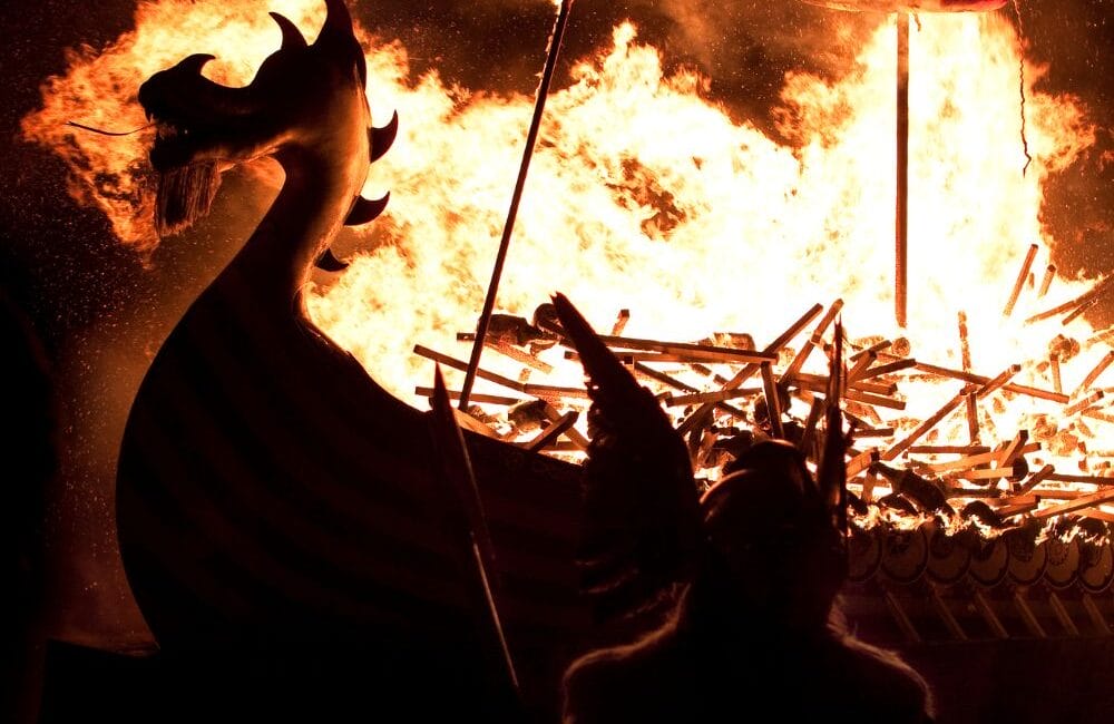 Torch-lit procession and burning of a Viking longship at the Up Helly Aa festival in Lerwick, Scotland, with participants in Viking costumes and a crowd of spectators.