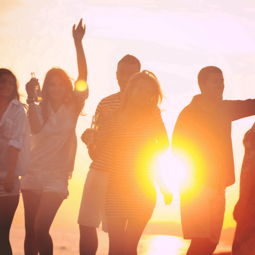 Young people dancing at sunset during a beach festival in Barcelona.