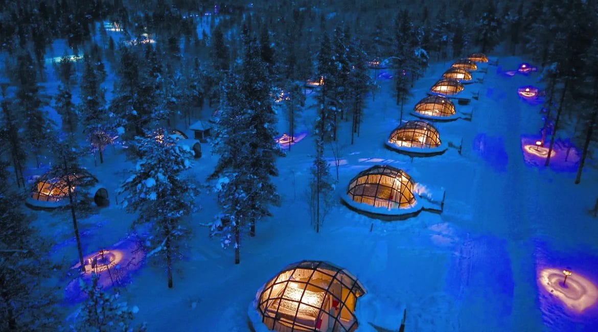 Kakslauttanen Arctic Resort East Village Finland - Exterior view of glass-roofed igloos in snowy landscape, perfect for watching the Arctic night sky.