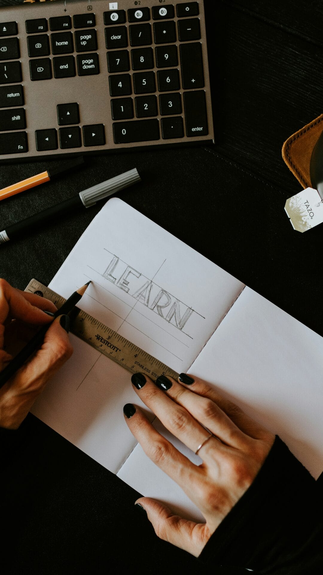 The hand of a woman writing the word LEARN on a piece of paper, symbolizing language learning