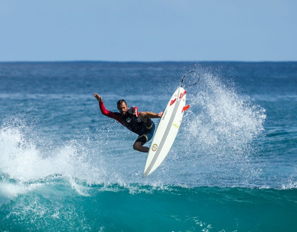 "Surfer tackling a wave in Klitmøller with Denmark's rugged coastline in the background